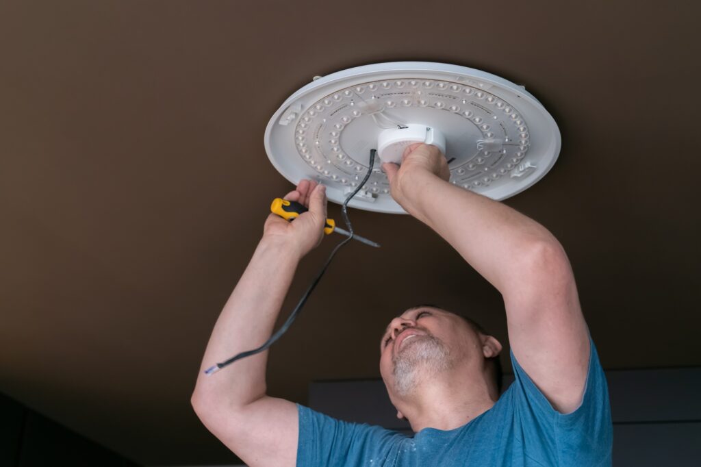 Un homme en train d’installer un lustre au plafond