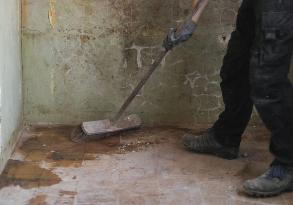 A young man sweeps the floor with a broom.