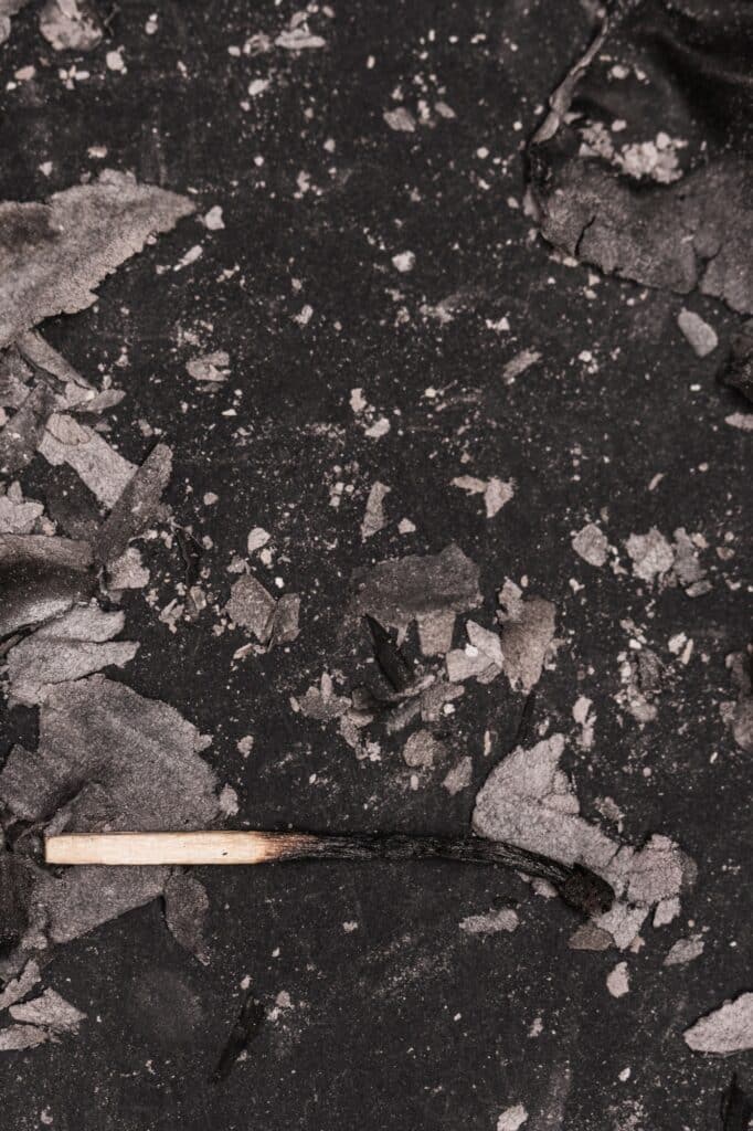 Burnt Match and Ashes on Dark Surface