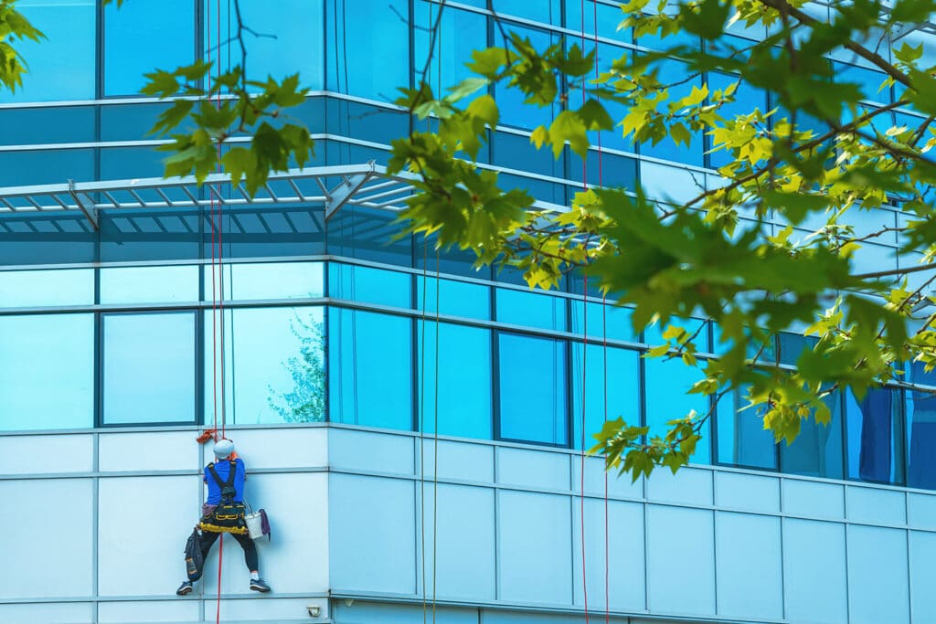 Homme qui nettoie des vitres, nettoyant la façade d’un bureau